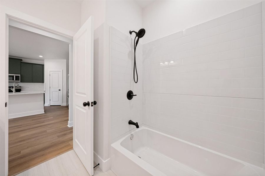 A pristine bath and shower area features sleek subway tile and modern black fixtures. A pristine bath and shower area features sleek subway tile and modern black fixtures.