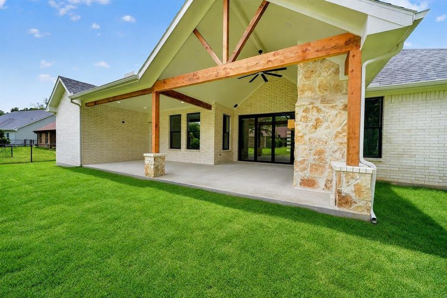Expansive concrete patio featuring a vaulted ceiling with exposed wood beams and a ceiling fan Expansive concrete patio featuring a vaulted ceiling with exposed wood beams and a ceiling fan