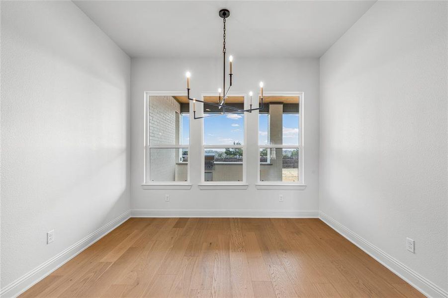 Unfurnished dining area featuring light wood-type flooring and hanging lights