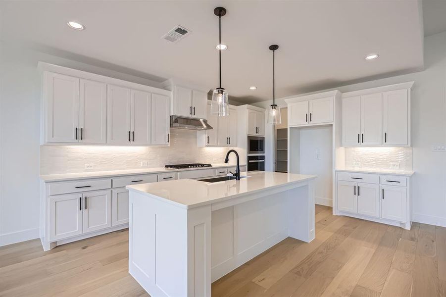 Kitchen featuring a sink, under cabinet range hood, light wood-type flooring, decorative backsplash, and recessed lighting Kitchen featuring a sink, under cabinet range hood, light wood-type flooring, decorative backsplash, and recessed lighting