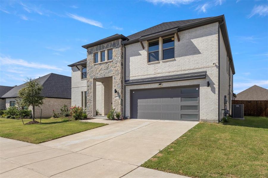 View of front of home featuring a front lawn, driveway, and a garage