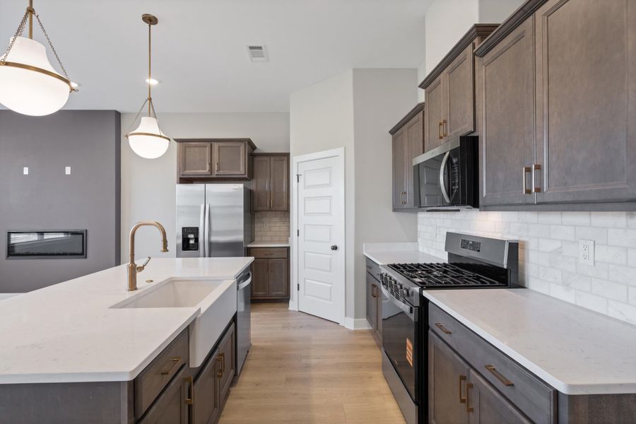 Kitchen featuring dark wood cabinetry, light wood-finish flooring, white countertops, and a subway tile backsplash