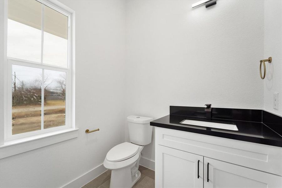 The powder bath located on the first level. Quartz countertops, an undermount sink & sleek hardware adorn this contemporary space.