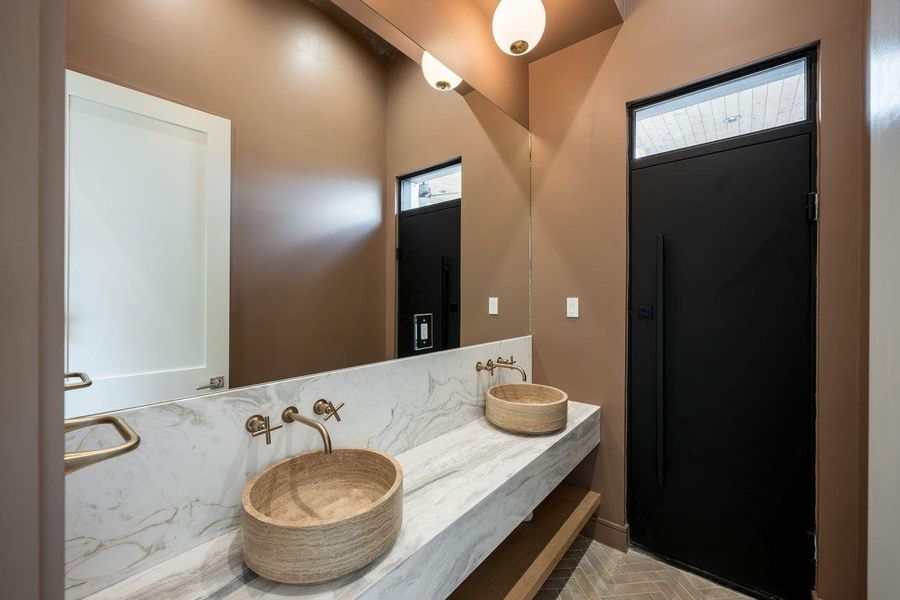Earthy tones and elevated finishes converge in this thoughtfully curated bath. A custom floating counter, artisan-inspired sinks, and warm brass accents transform everyday rituals into moments of understated luxury.