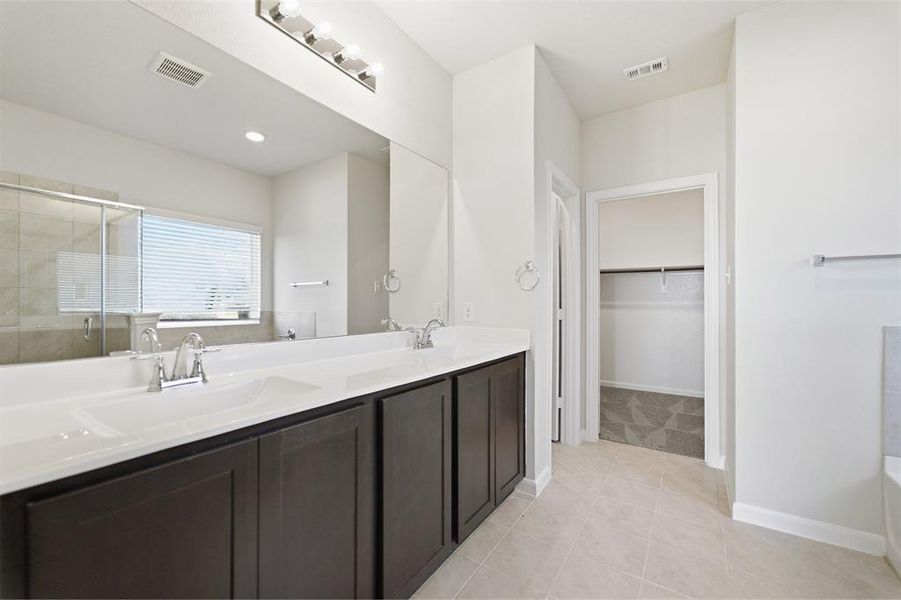Dual vanity featuring integrated sinks, dark wood-finish cabinetry, and chrome fixtures Dual vanity featuring integrated sinks, dark wood-finish cabinetry, and chrome fixtures