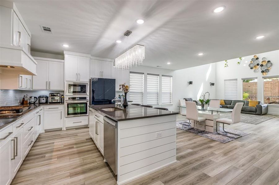 This luxury kitchen shines with stainless steel appliances, a spacious center island, and an open flow into the oversized dining area. Bright white cabinetry, abundant windows filling the space with natural light, and a mix of statement fixtures and recessed lighting create a truly stunning heart of the home! This luxury kitchen shines with stainless steel appliances, a spacious center island, and an open flow into the oversized dining area. Bright white cabinetry, abundant windows filling the space with natural light, and a mix of statement fixtures and recessed lighting create a truly stunning heart of the home!