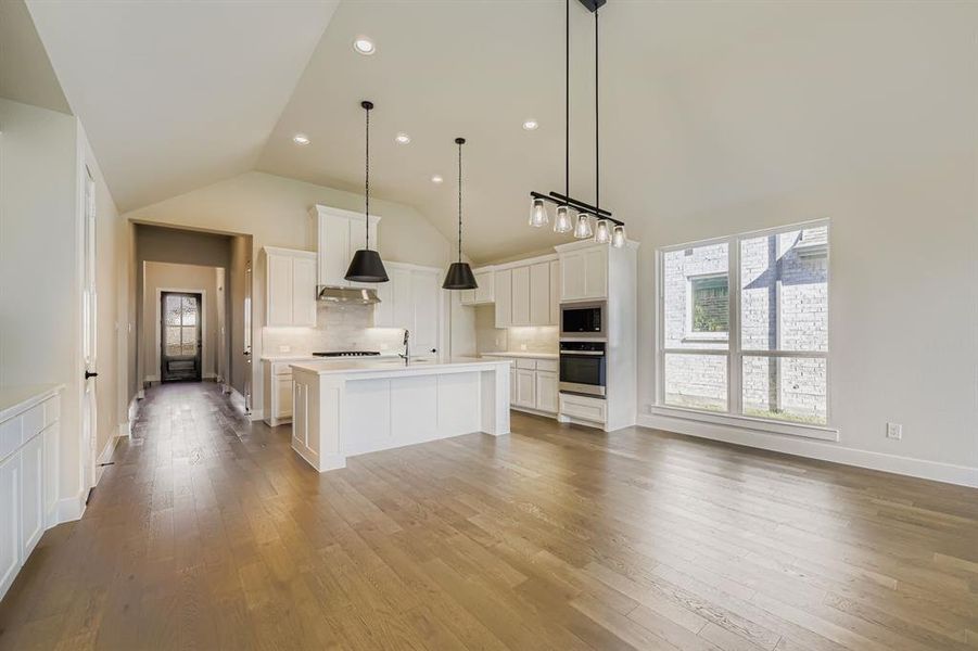 Kitchen featuring tasteful backsplash, white cabinets, a kitchen island with sink, light wood-style flooring, and recessed lighting Kitchen featuring tasteful backsplash, white cabinets, a kitchen island with sink, light wood-style flooring, and recessed lighting