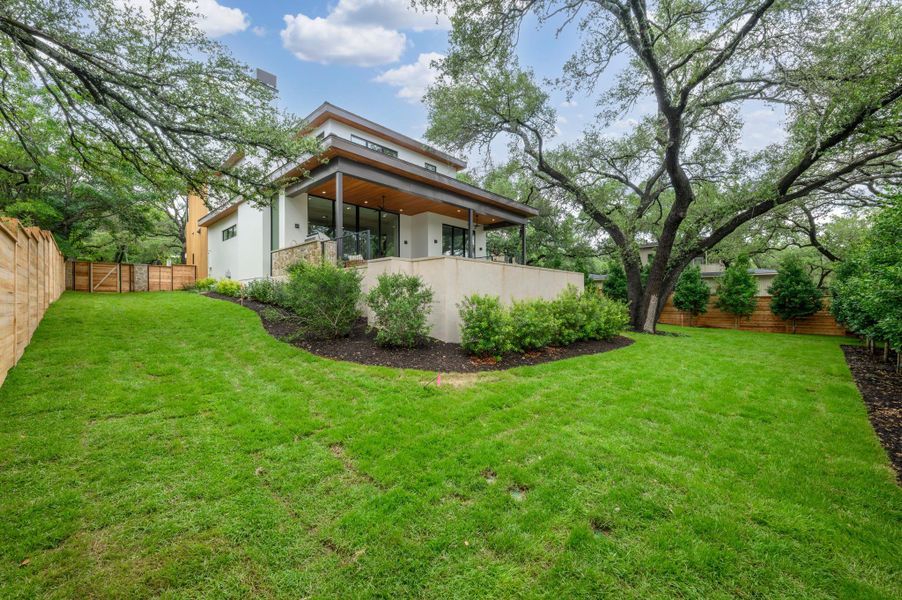 A vibrant green lawn and lush landscaping surround this modern home with an inviting covered patio. A vibrant green lawn and lush landscaping surround this modern home with an inviting covered patio.