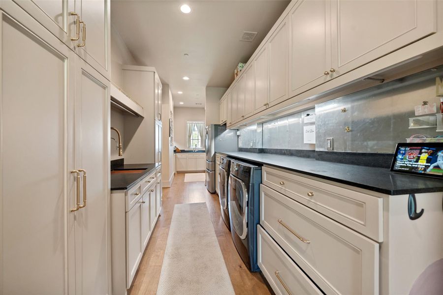 This expansive utility and mudroom offers both practicality and charm, with built-in lockers for organization, a large refrigerator, and a dedicated washer and dryer—providing a seamless space for daily routines, storage, and keeping life organized.
