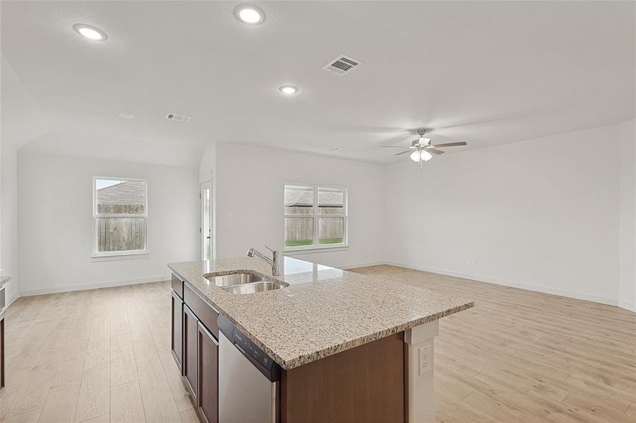 Kitchen with ceiling fan, a kitchen island with sink, light hardwood / wood-style flooring, dishwasher, and sink