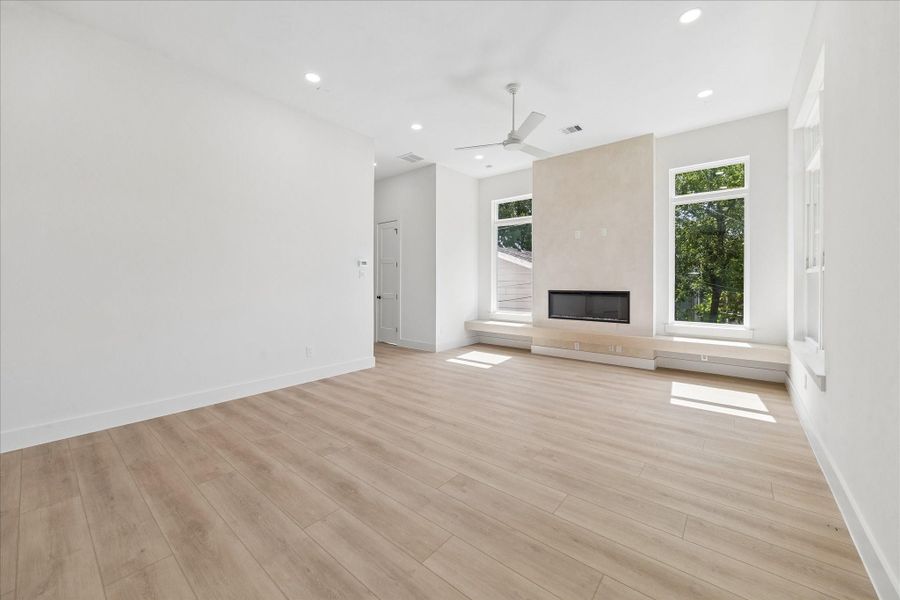 The linear fireplace is framed by a textured plaster accent wall, creating a dramatic focal point softened by warm wood tones and expansive windows.