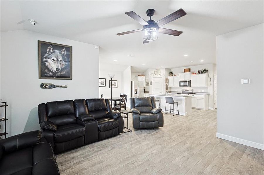 Living room featuring ceiling fan, light wood-style flooring, recessed lighting, baseboards, and vaulted ceiling