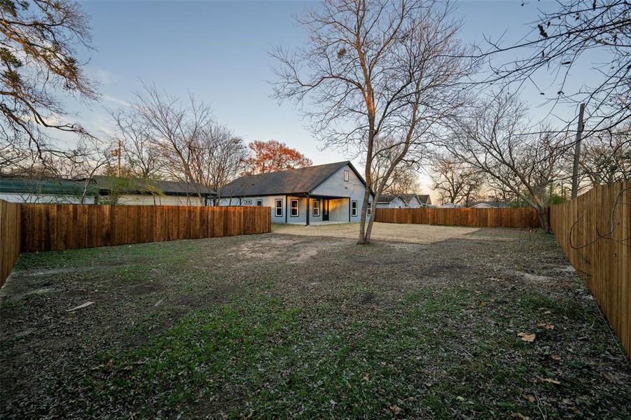 Yard at dusk with a fenced backyard and a patio area
