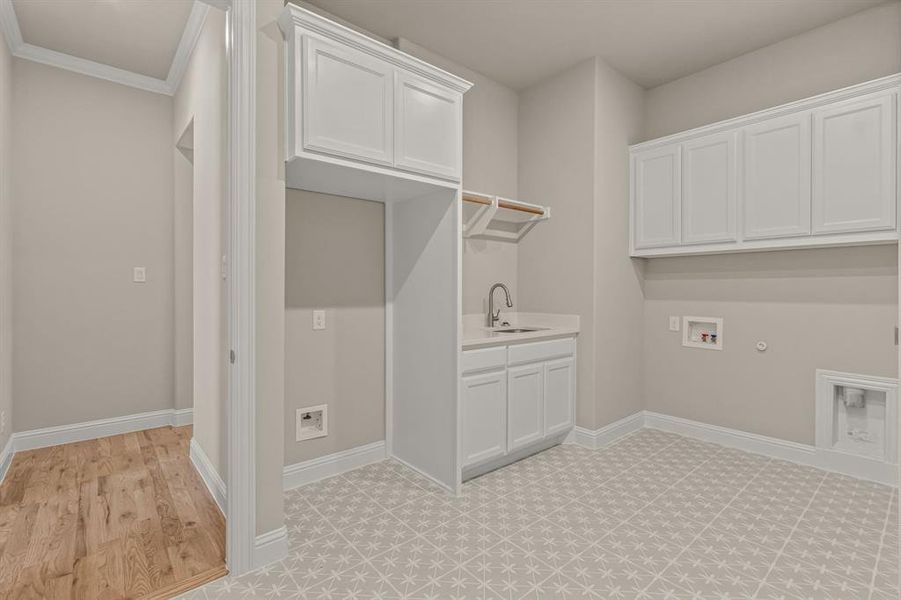 Laundry area with sink, hookup for a washing machine, cabinets, ornamental molding, and hookup for a gas dryer