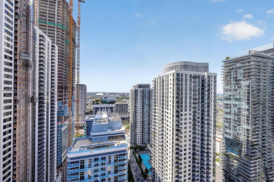 High-rise urban landscape featuring glass-facade residential towers, balconies with railings, and an outdoor swimming pool