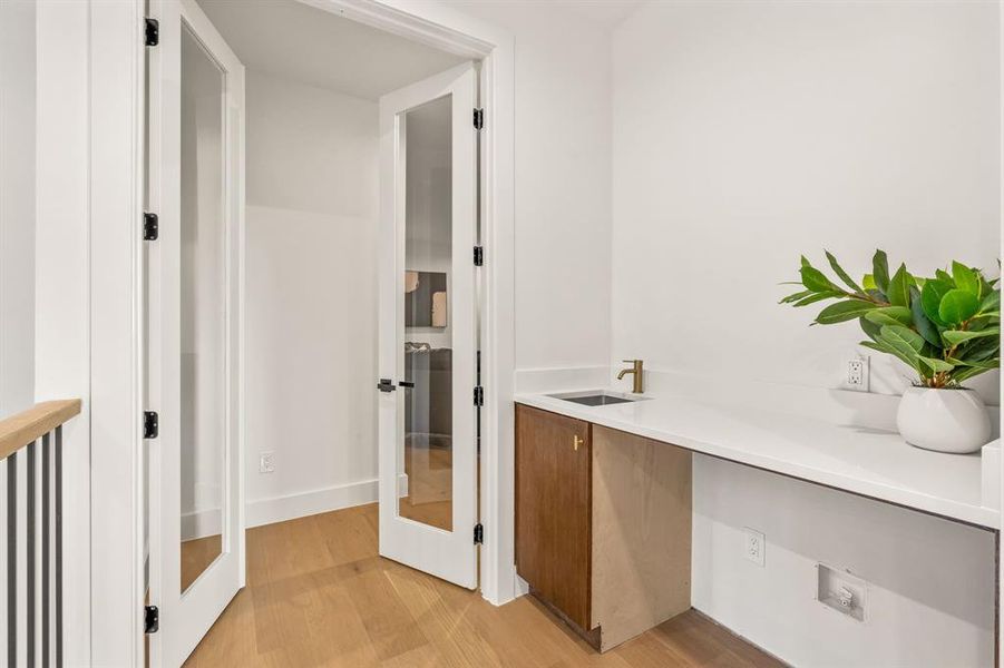 Hall featuring light wood-style floors and a sink Hall featuring light wood-style floors and a sink