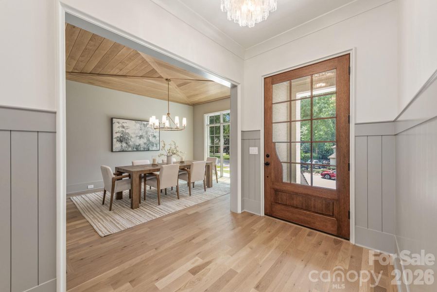 Welcoming foyer with gorgeous front door and dining room ceiling details