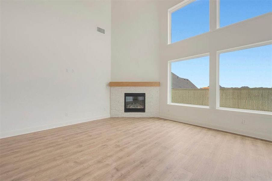 Spacious living area featuring a corner fireplace with white brick surround and wood mantle