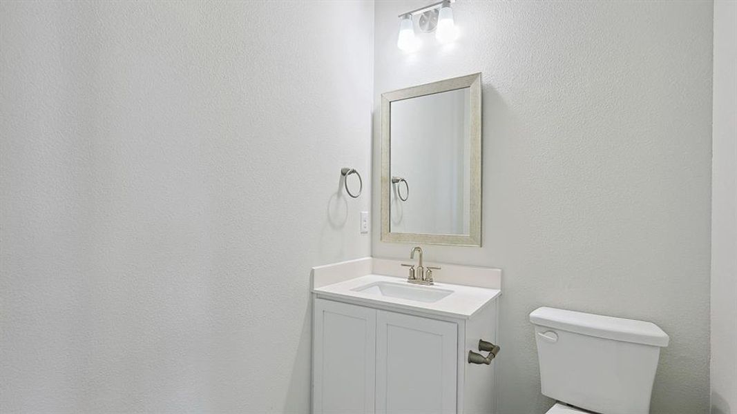 White vanity with a built-in sink, brushed nickel faucet, and a framed mirror