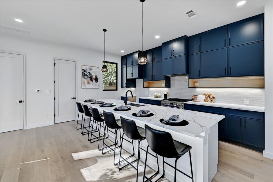 Kitchen with blue cabinets, range, visible vents, and a sink