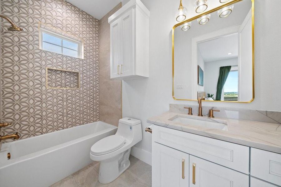 Chic and contemporary ensuite bath featuring bold patterned tile, elegant gold finishes, and a quartz-topped vanity. Thoughtful touches like built-in shelving and designer lighting add both function and flair.