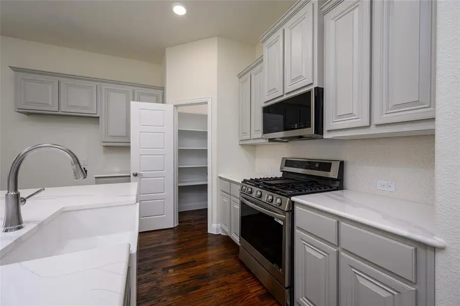 Kitchen with sink, appliances with stainless steel finishes, light stone countertops, and dark wood-type flooring
