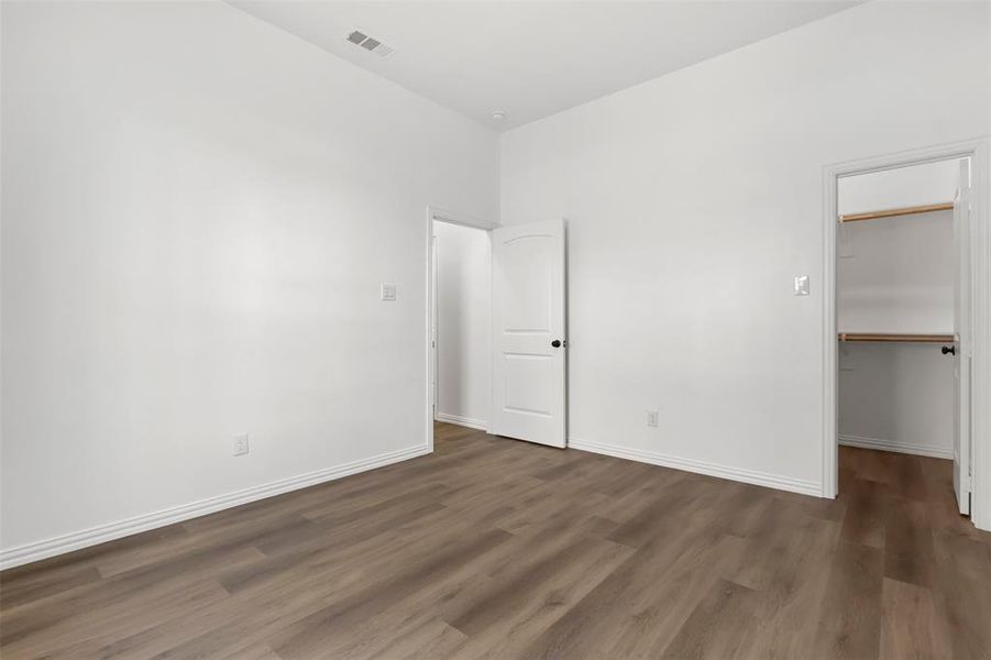 Unfurnished bedroom featuring a walk in closet, a closet, and dark wood-type flooring