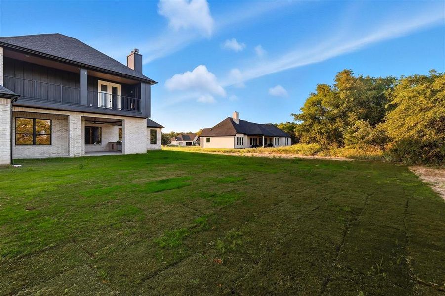 View of green lawn with a patio and a balcony View of green lawn with a patio and a balcony