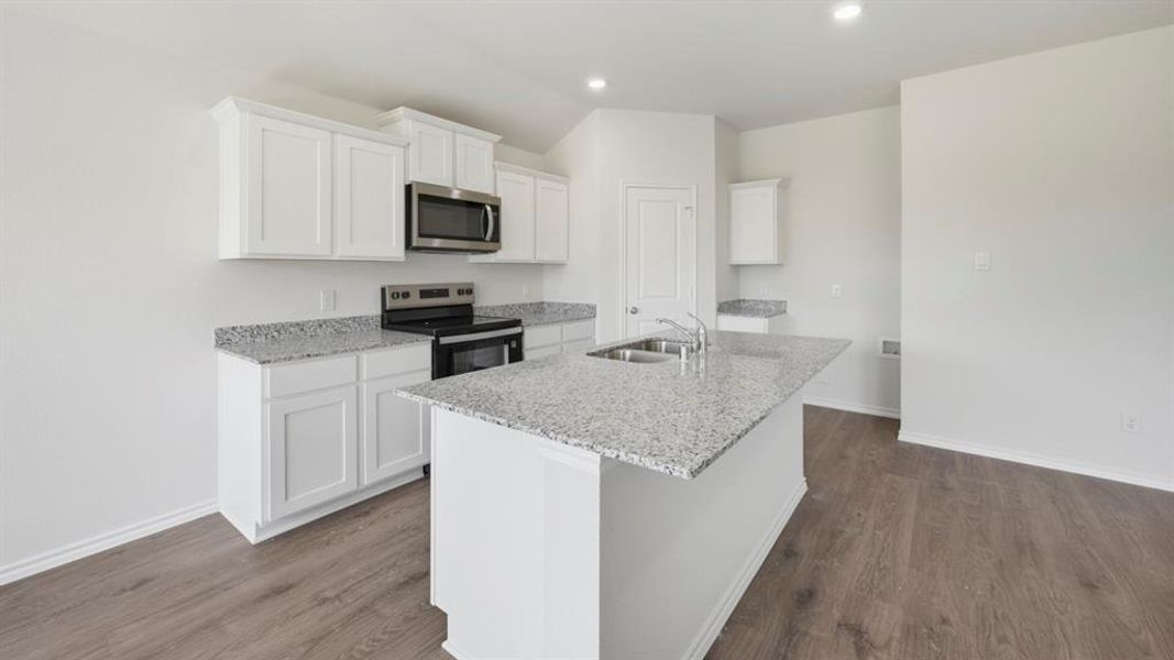 Kitchen with white cabinetry, stainless steel appliances, light stone countertops, an island with sink, and recessed lighting