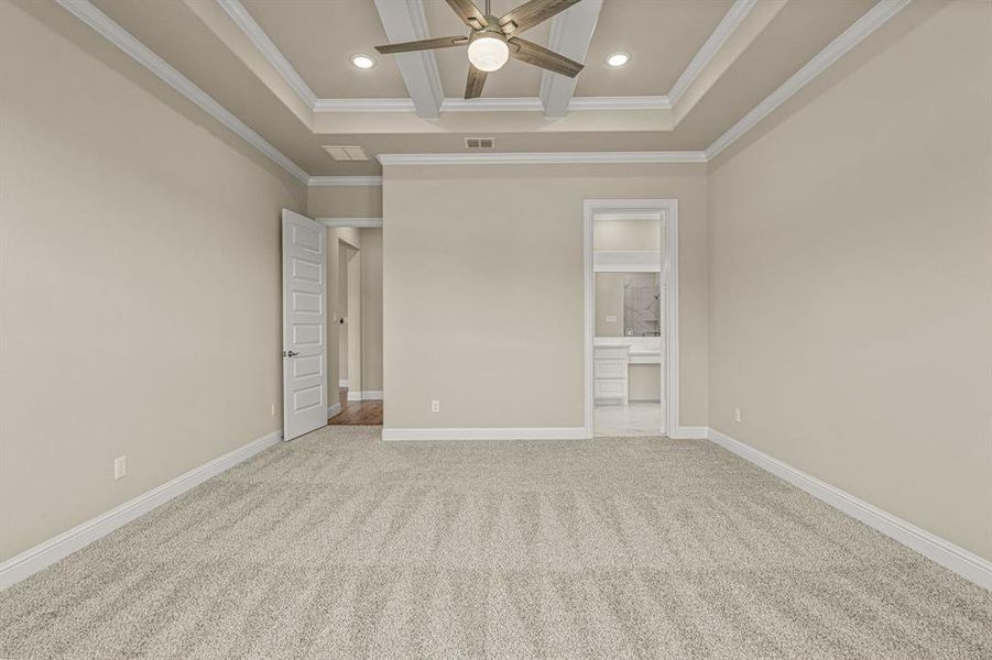 Unfurnished bedroom featuring ceiling fan, carpet flooring, beamed ceiling, and a tray ceiling