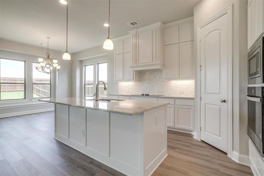 Kitchen with sink, white cabinetry, an island with sink, and light hardwood / wood-style flooring