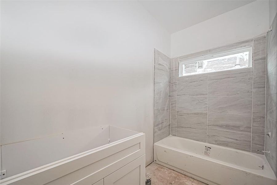 A well-planned bath with a shower-tub combo accented by tiled walls. The vanity, designed with ample under-storage, offers plenty of room for everyday essentials.