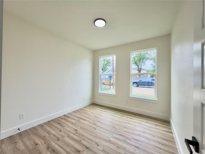 Bright interior space featuring light-colored walls, wood-finish flooring, and white baseboards