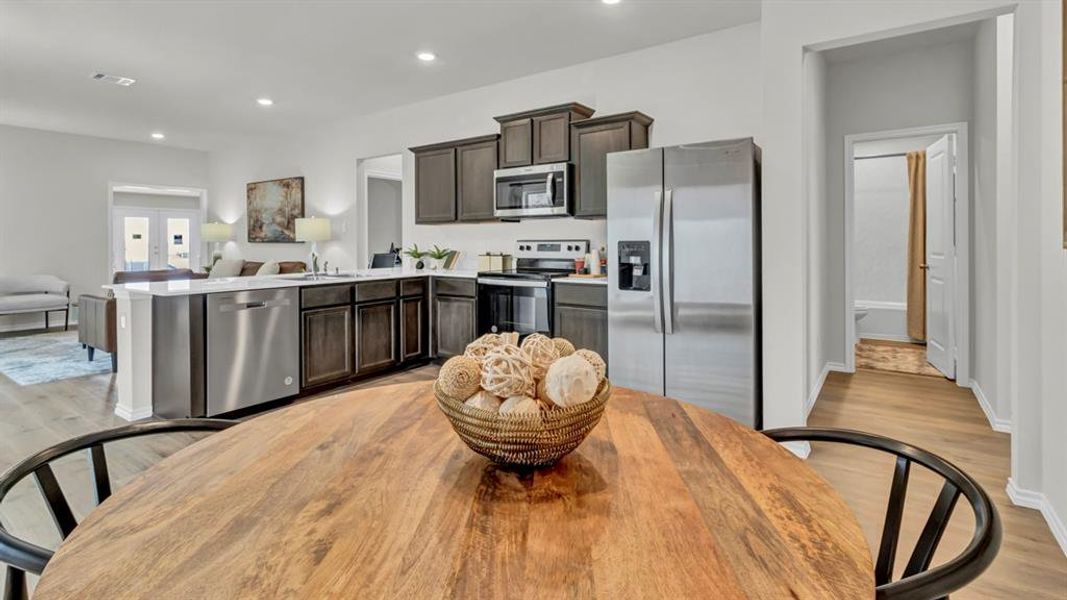 Kitchen with stainless steel appliances, open floor plan, light wood-style flooring, light countertops, and recessed lighting Kitchen with stainless steel appliances, open floor plan, light wood-style flooring, light countertops, and recessed lighting