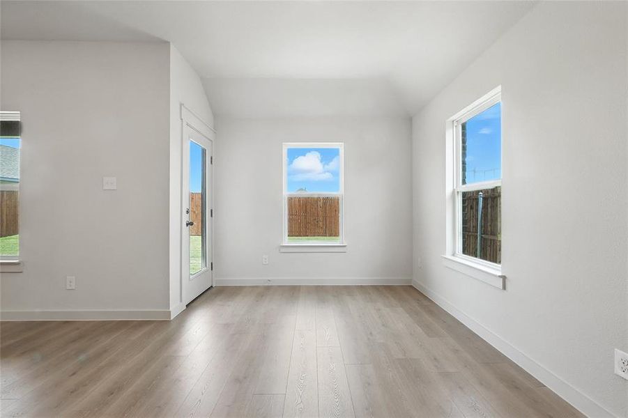 Unfurnished room with light wood-style floors and vaulted ceiling