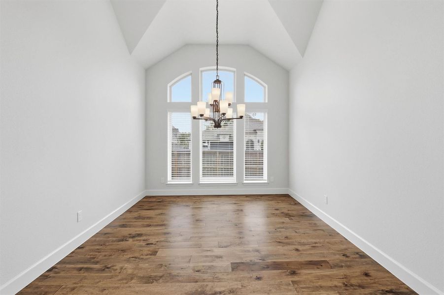 Imagine your dining room table beneath this chandelier. Soaring 12-foot vaulted ceilings create a sense of grandeur that makes every dinner feel like an occasion. The arched windows flood the space with natural light, warm engineered hardwood floors ground the room beautifully, and there is simply enough space to seat everyone you love. Holiday gatherings, milestone celebrations, Sunday dinners; this room was made for all of it.