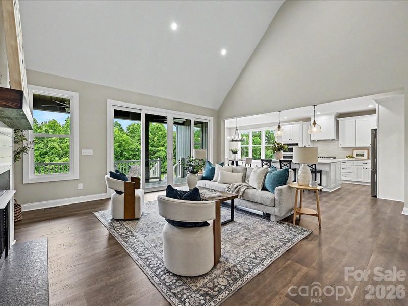 The stunning great room showcases soaring vaulted ceilings, expansive windows with scenic views, dozy gas fireplace and an open-concept layout that seamlessly connects the living, dining, and kitchen spaces for effortless entertaining.