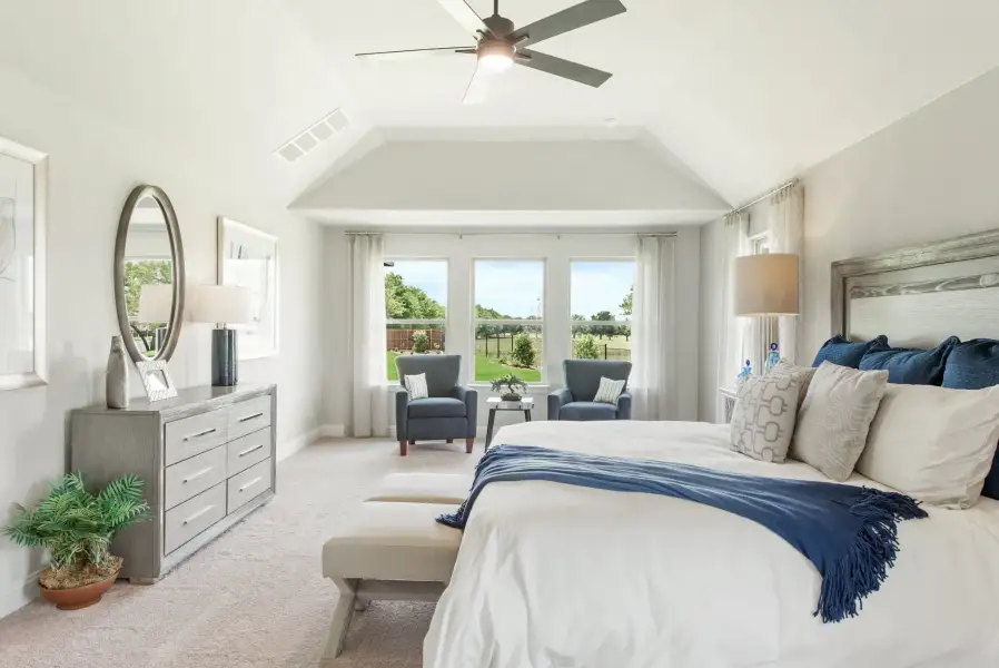 Master bedroom with vaulted ceiling, ceiling fan, sitting area by bay windows, and carpet flooring