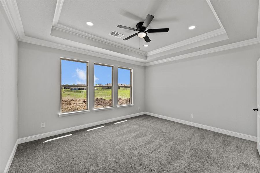 Carpeted empty room featuring a raised ceiling, crown molding, ceiling fan, and recessed lighting Carpeted empty room featuring a raised ceiling, crown molding, ceiling fan, and recessed lighting