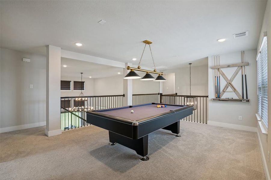 Expansive loft area featuring neutral carpeting and a decorative ceiling light fixture