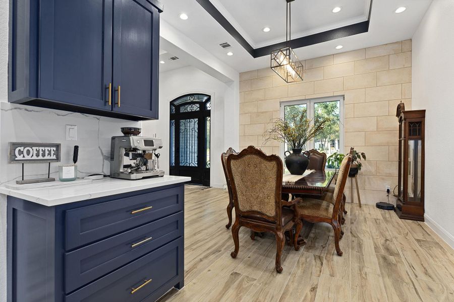 Dining area with a raised ceiling, light wood-style floors, and recessed lighting Dining area with a raised ceiling, light wood-style floors, and recessed lighting
