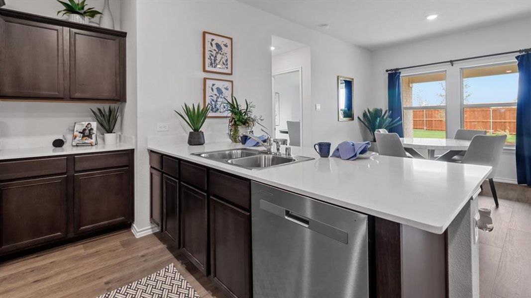 Kitchen with dark wood finish cabinetry, stainless steel dishwasher, light wood-style flooring, recessed lighting, and a peninsula Kitchen with dark wood finish cabinetry, stainless steel dishwasher, light wood-style flooring, recessed lighting, and a peninsula