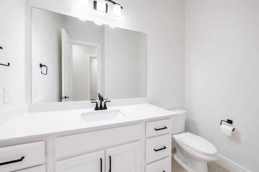Bathroom featuring a white vanity with an undermount sink, a white countertop, and black hardware