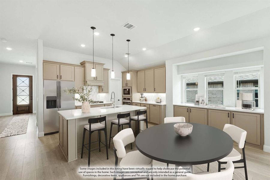 Open kitchen and dining area with tan cabinets, center island, pendant lights, and round dining table