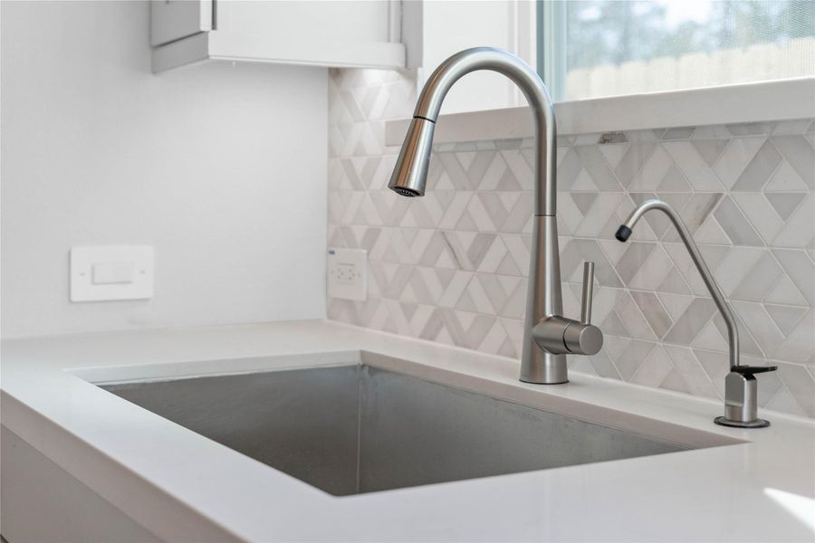 The modern stainless steel undermount sink is perfectly situated beneath a bright window, offering a pleasant view of the outdoors. The modern stainless steel undermount sink is perfectly situated beneath a bright window, offering a pleasant view of the outdoors.