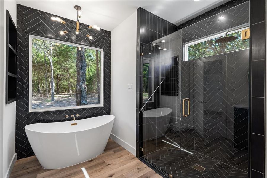 Full bathroom featuring a soaking tub, light wood-style flooring, tile walls, a shower, and a chandelier