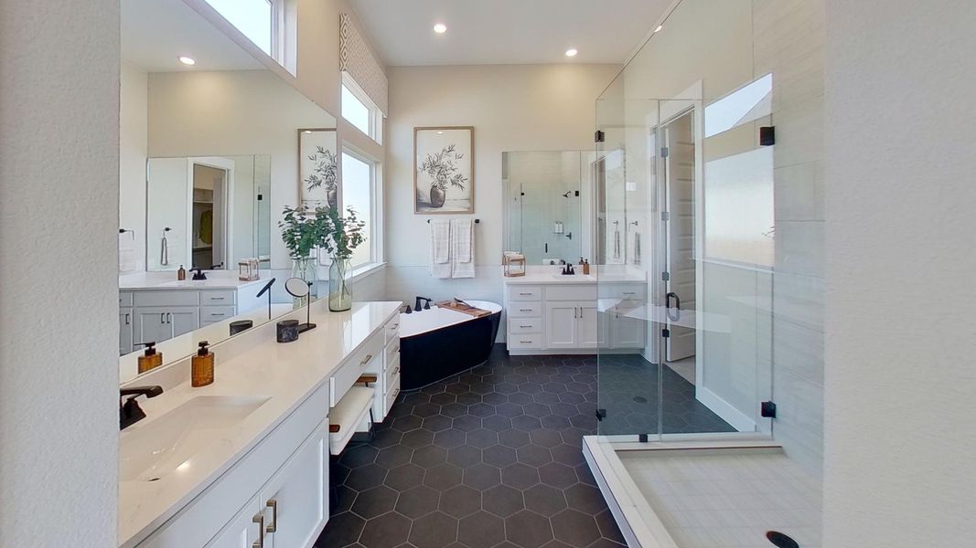 Full bathroom featuring two vanities, a stall shower, dark tile patterned floors, a soaking tub, and recessed lighting