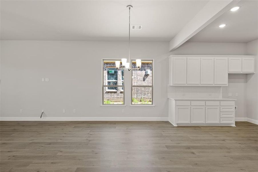 Unfurnished dining area featuring light wood-style floors, a chandelier, recessed lighting, and beamed ceiling