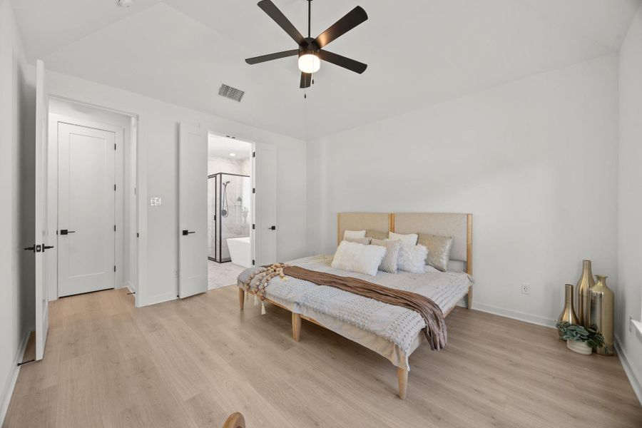 Bedroom with lofted ceiling, light wood-style floors, ceiling fan, and connected bathroom