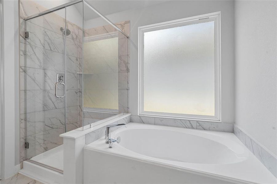 This additional view of the primary bath showcases a walk-in shower with tile surround and a separate garden tub perfect for soaking after a long day.